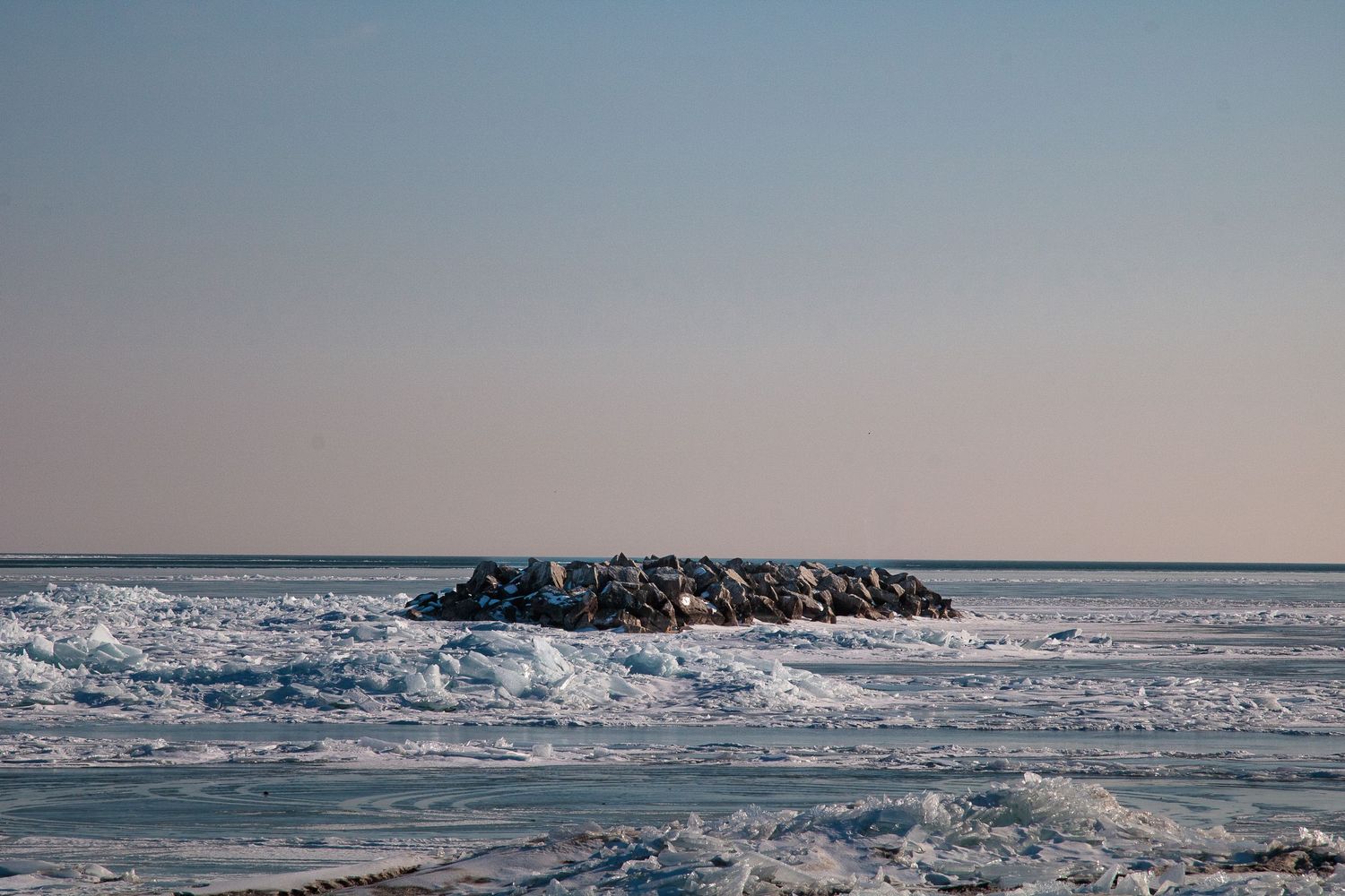 A series of panoramic photographs showing winter ice formations along Lake Michigan's shoreline at sunset.