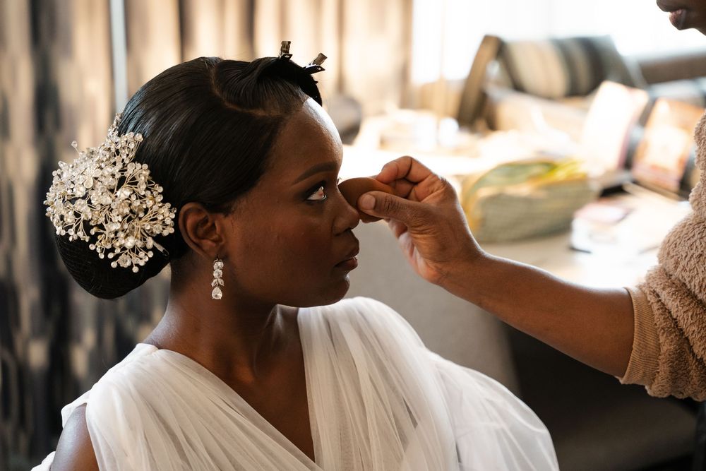 Makeup artist applying lipstick to a bride during wedding day preparations.