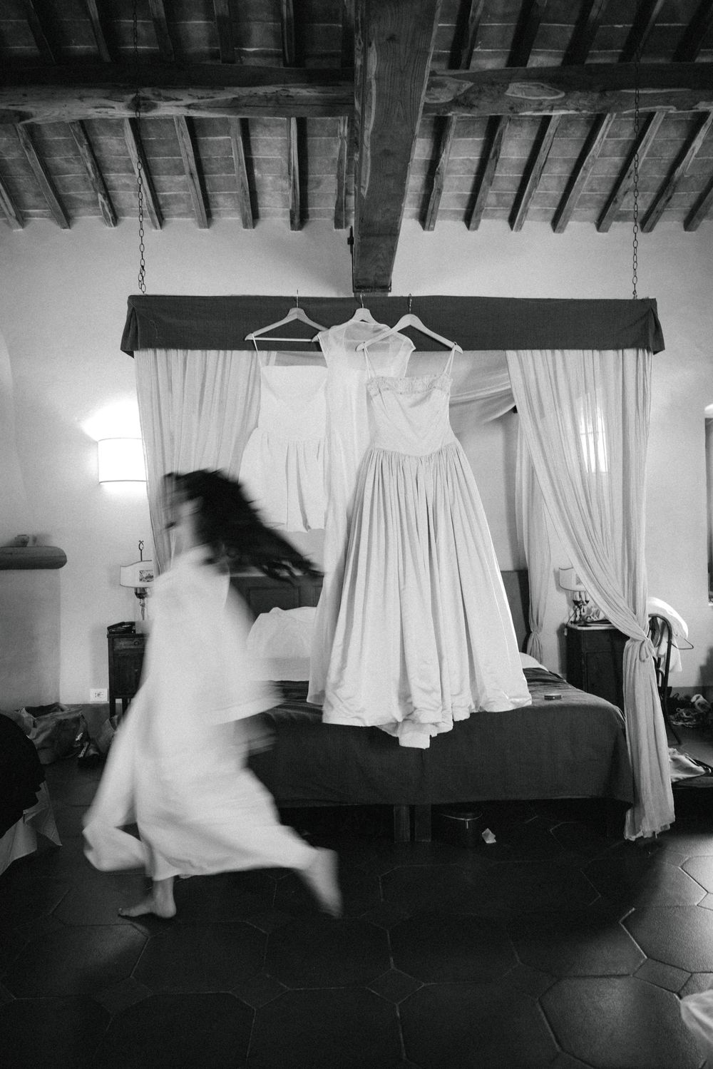 A series of black and white photographs showing white dresses or garments suspended and floating against a dark background.