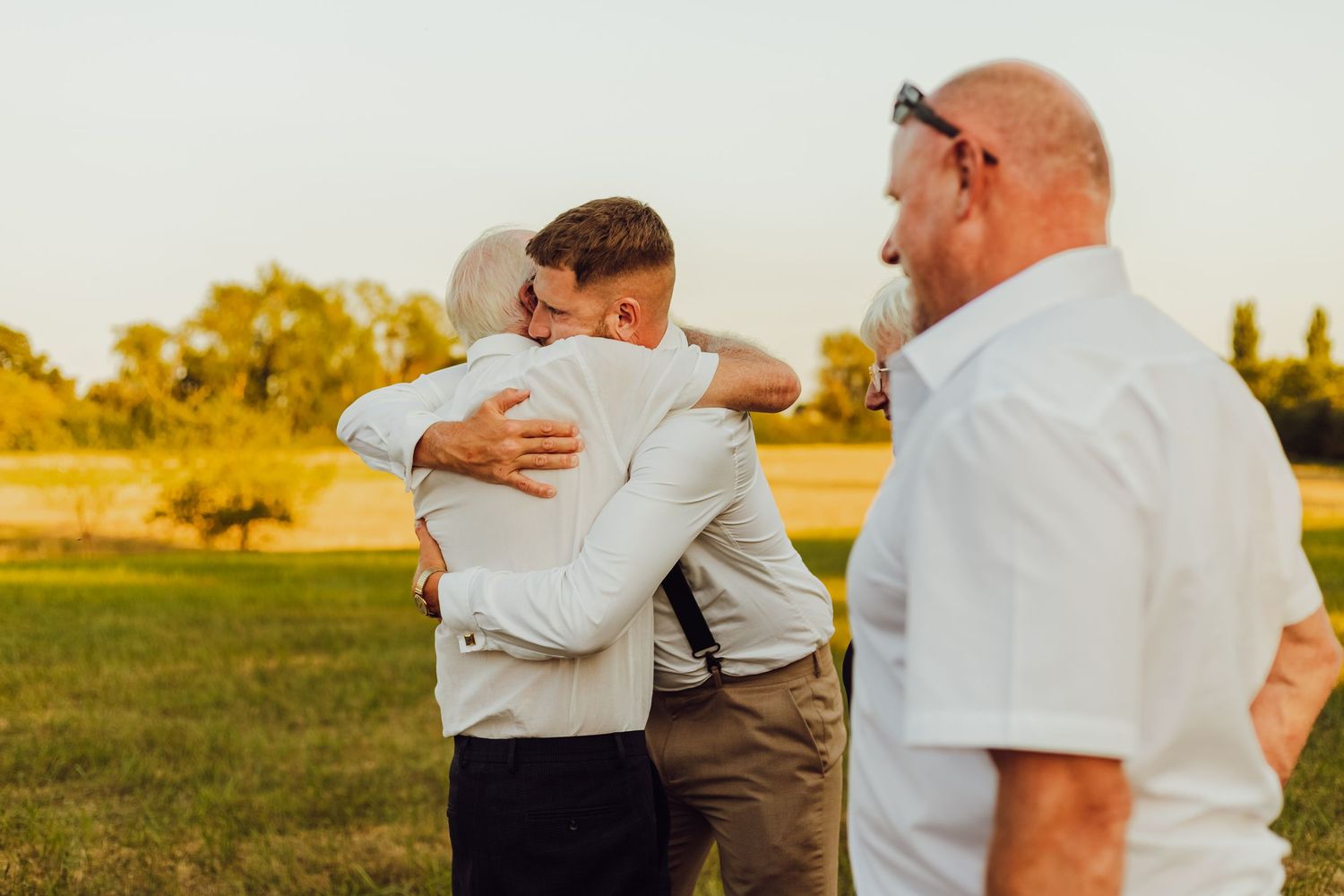Wedding guests interacting naturally on a field, candid and relaxed moments.
