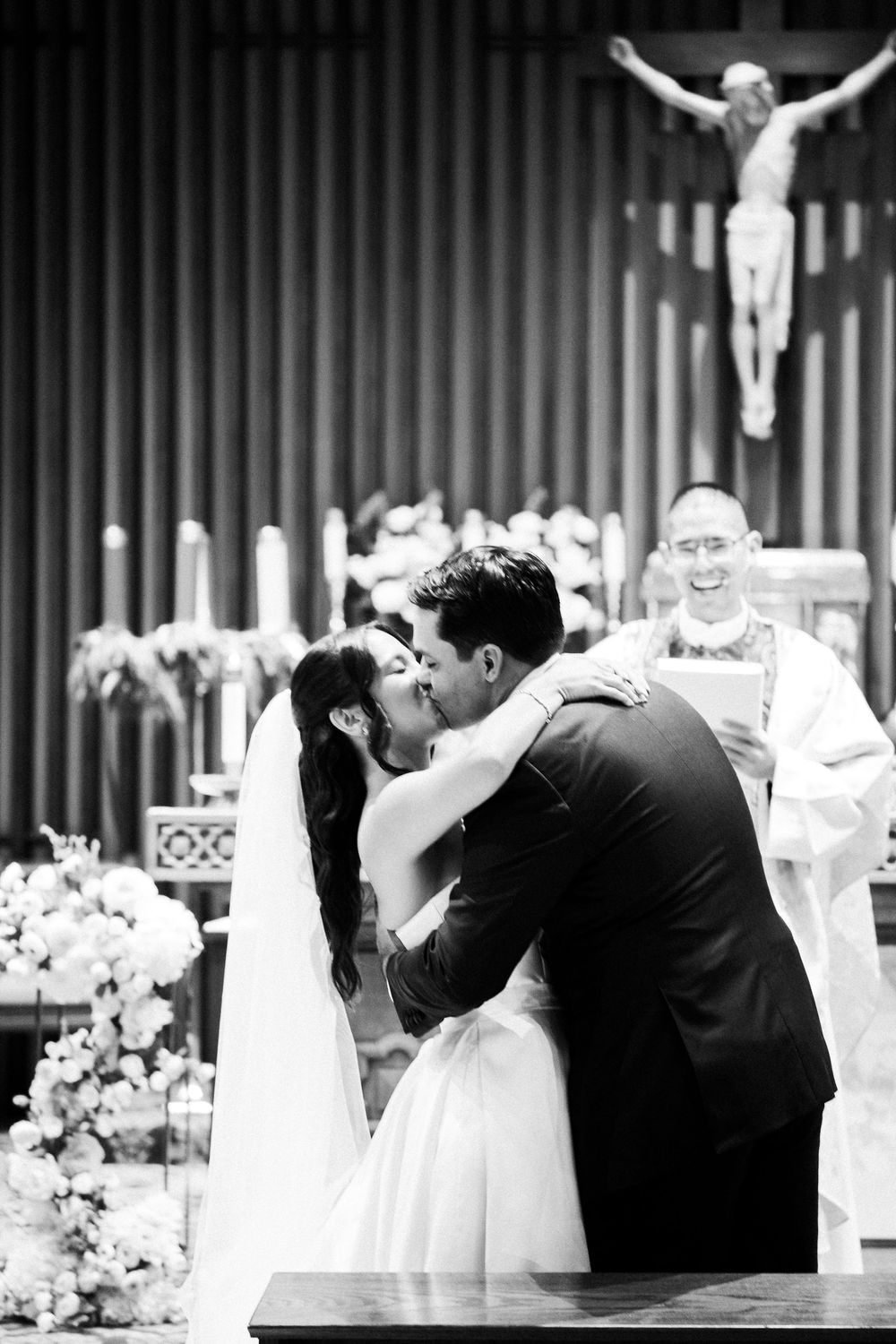 Black and white photo series showing a romantic wedding kiss in a church with a crucifix visible in the background.