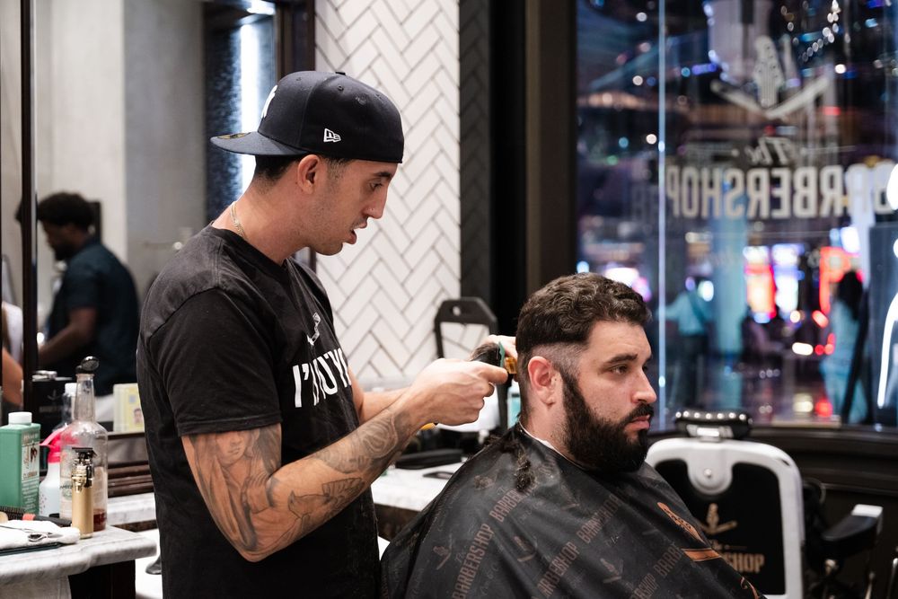 Barber shop interior with multiple stations showing chairs, mirrors and professional styling equipment in modern setting.