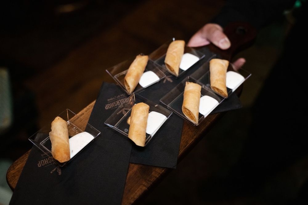 Cigarette butts arranged in a line on black fabric against a dark wooden surface.