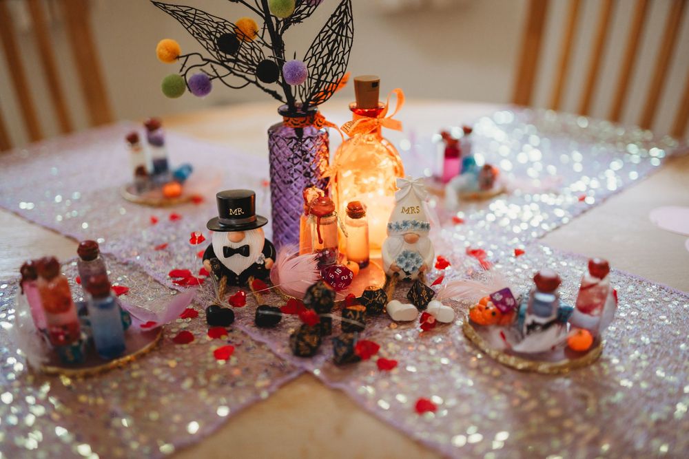 Wedding reception table decorated with colorful rose petals, candles and butterfly decorations in warm lighting.