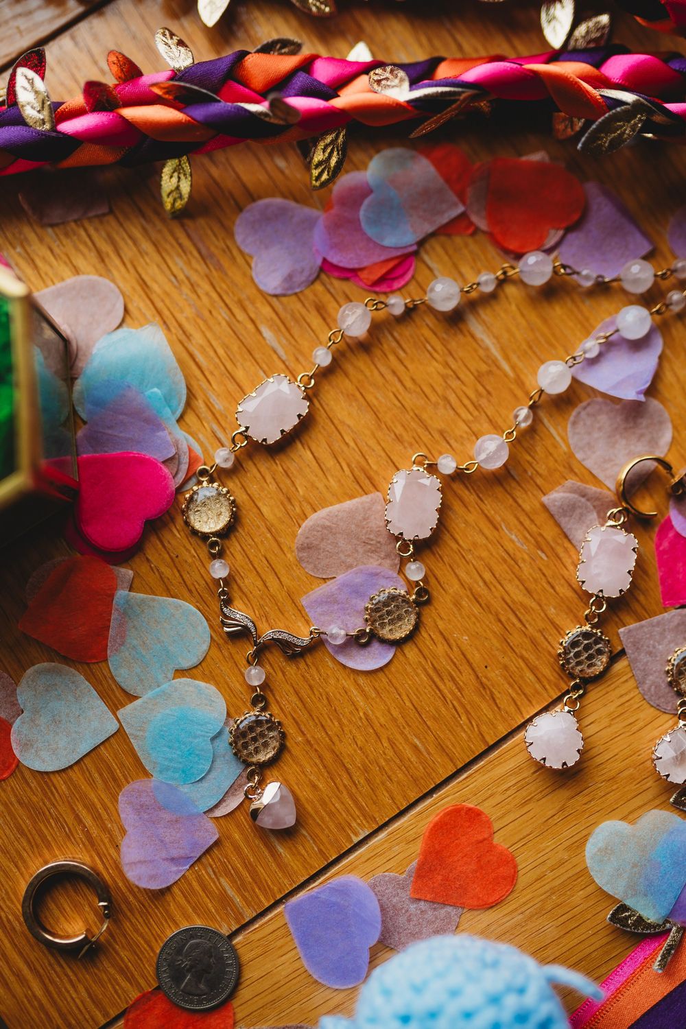 Colorful paper heart confetti and vintage keys scattered on a wooden surface create a whimsical decorative display.