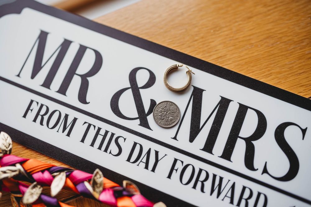 Decorative wedding sign displays 'Mr & Mrs' text in elegant typography on a wooden surface.