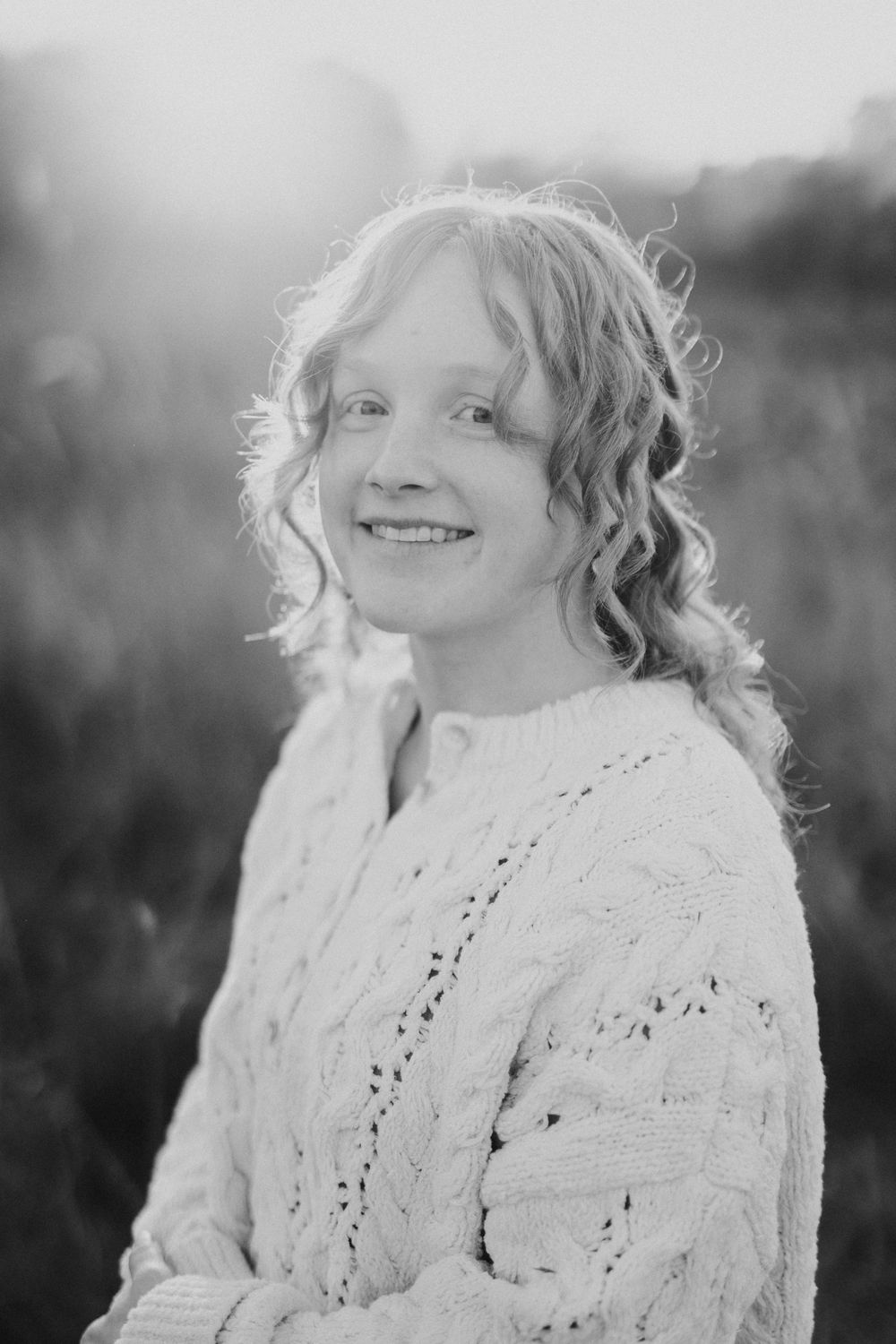 Black and white portrait series showing joyful expressions and curly hair against a natural outdoor background.