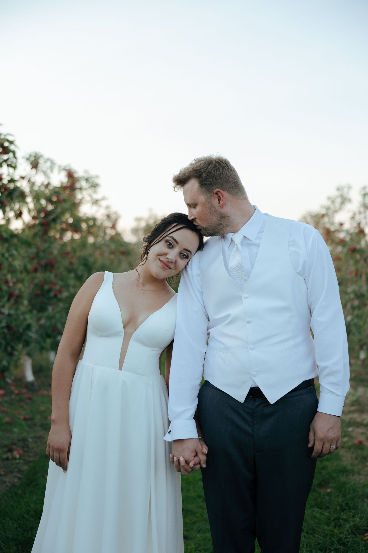 A couple in wedding attire shares intimate moments together while holding hands in an outdoor garden setting.