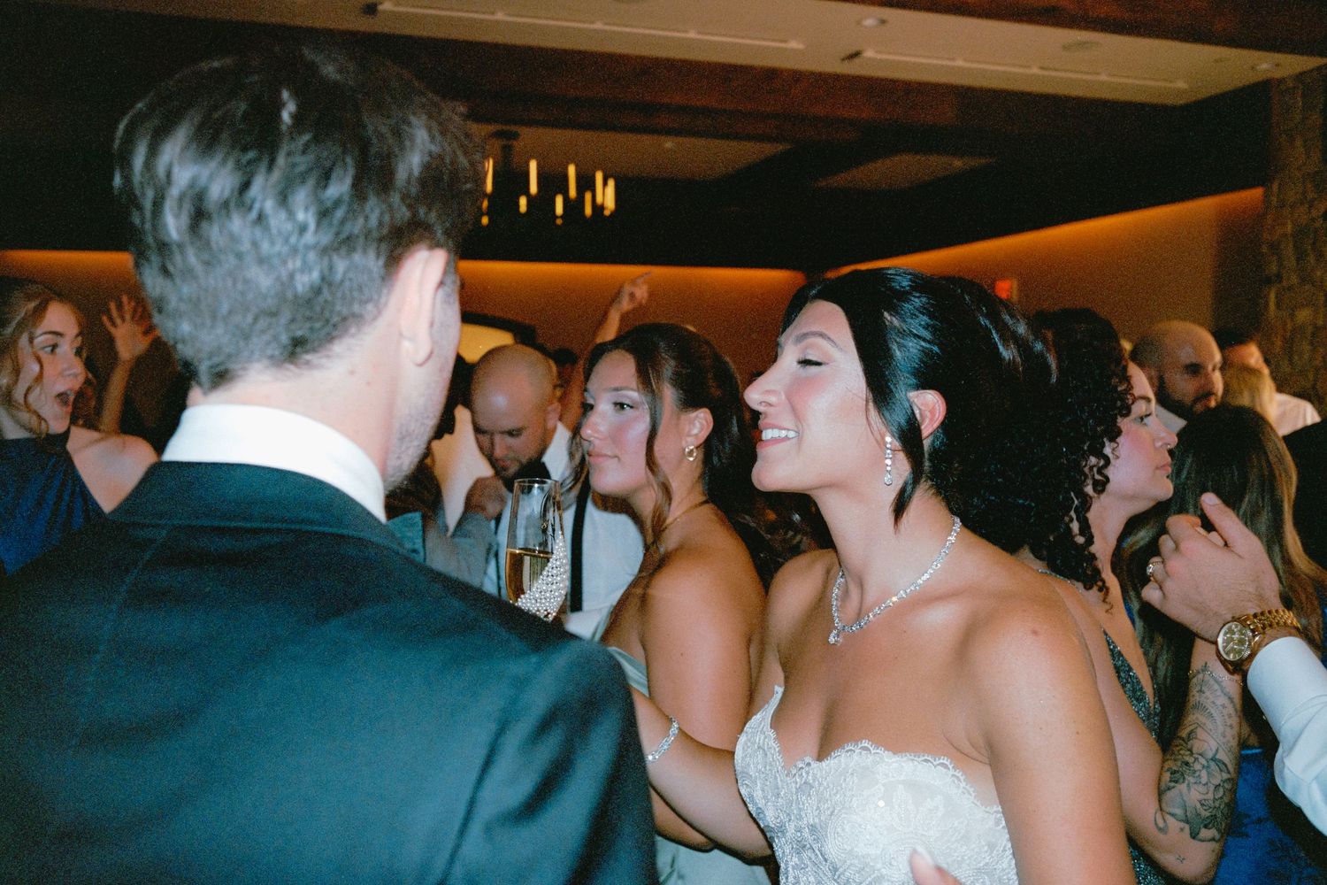 A row of wedding guests dancing and celebrating together at an indoor reception venue.