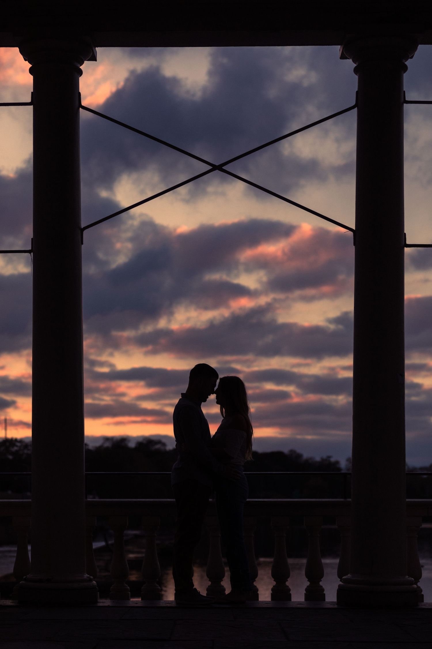 Silhouettes of people against a dramatic sunset sky with architectural columns.