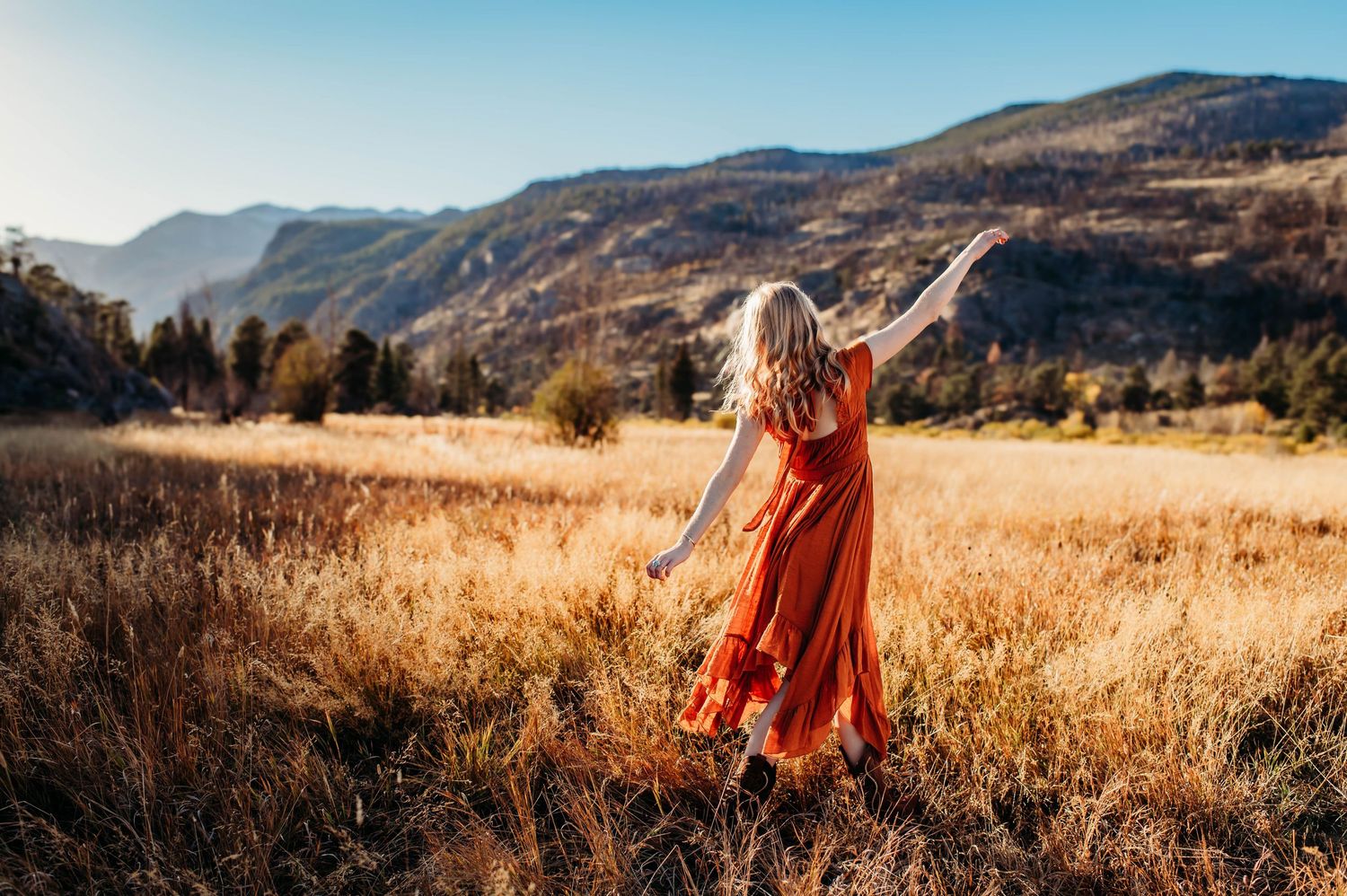 A person in a white lace dress walks through golden sunlit fields during sunset creating a dreamy ethereal scene.