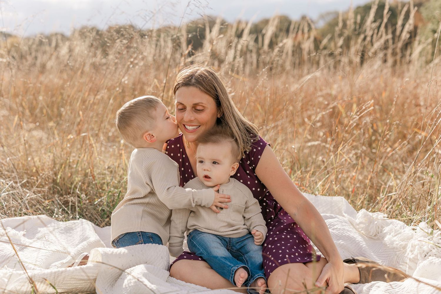 Family relaxing together in a golden wheat field during sunset, creating intimate lifestyle moments.