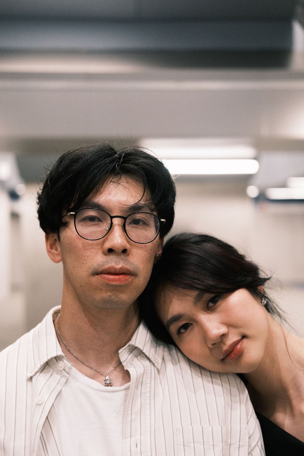 A couple in a romantic pose wearing white clothing against a light background.