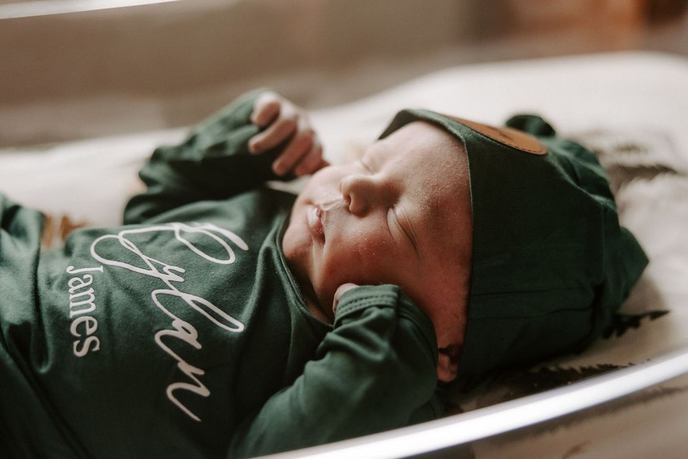 A person wearing a green hospital gown lies on a medical bed in a healthcare setting.