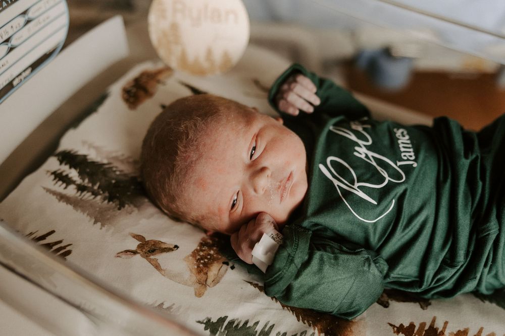 Multiple views of a resting infant in a green sleeper on white sheets.