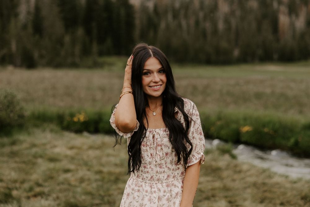 A series of outdoor portrait photos showing a person in a floral dress posing in a natural field setting at sunset.