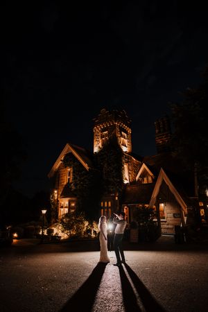 A romantic nighttime wedding photo sequence showing silhouettes against illuminated gothic stone buildings.