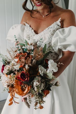 Close-up shots of elegant white bridal bouquets featuring rustic orange and white flowers with eucalyptus greenery.