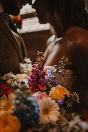 Close-up view of colorful dried and fresh flowers arranged together in a moody, dark setting with warm lighting.