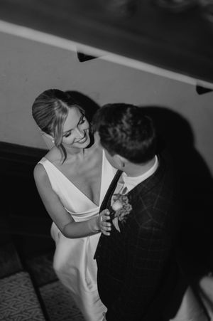 A romantic black and white wedding photograph showing a tender moment between a couple in formal attire.