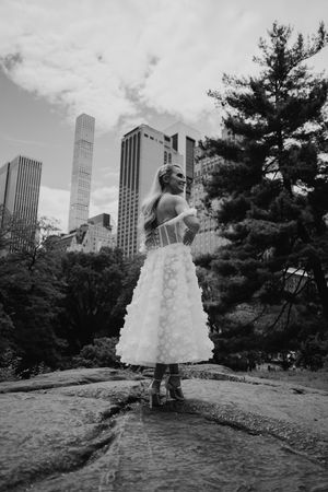 A wedding dress silhouette against the New York City skyline in Central Park during a black and white photo series.