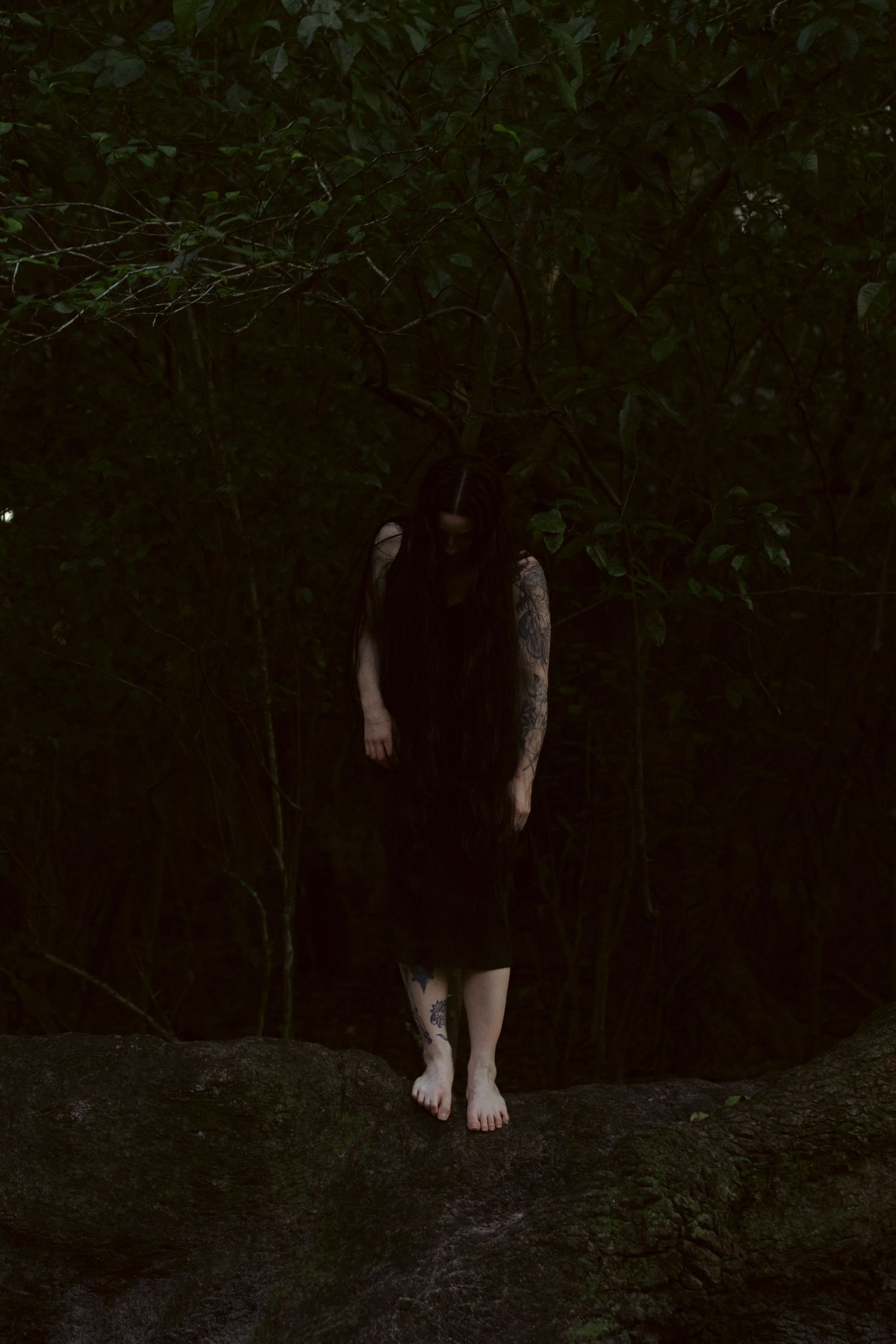 A dark and eerie sequence of cropped photos showing bare feet walking on forest ground at night.