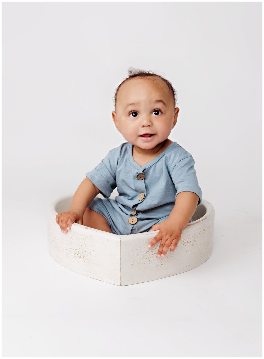 little boy sitting in a heart bowl on a light background.