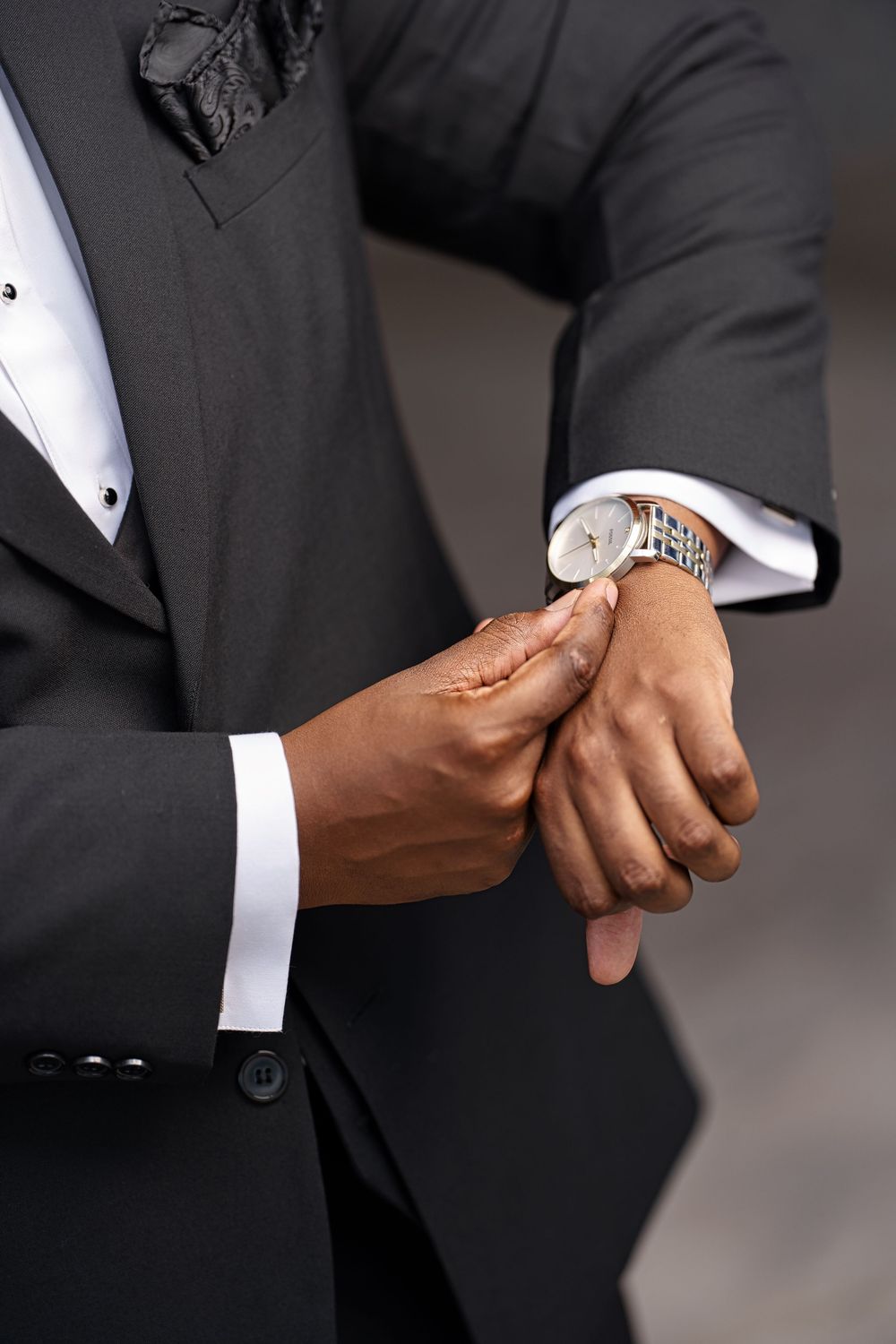 Close-up series of hands adjusting white dress shirt cuffs and sleeves on a black suit jacket.