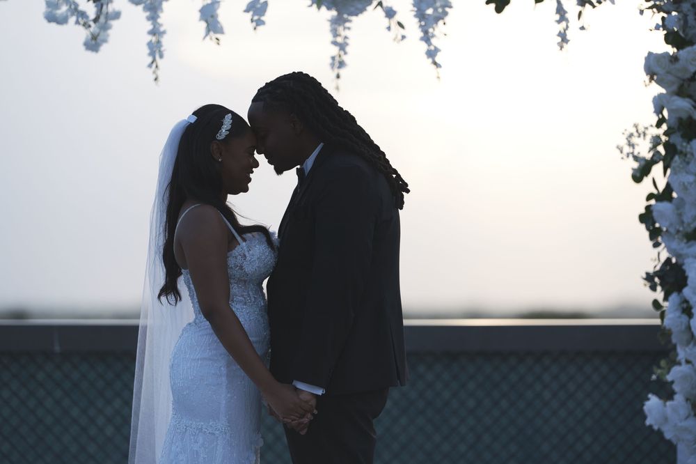A romantic silhouette of a couple embracing against a bright background during a wedding photo session.