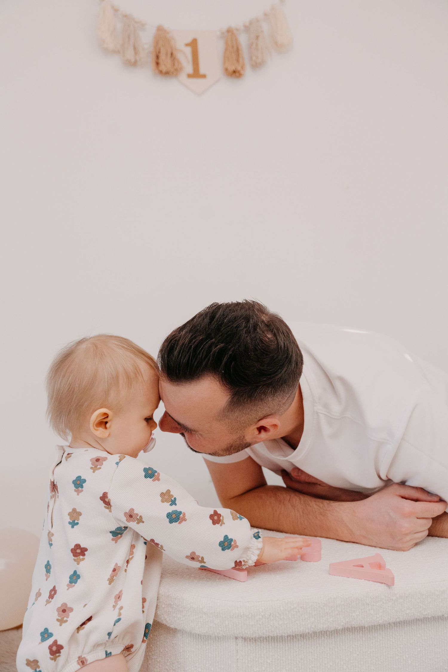 A series of tender moments between a parent and baby in floral pajamas on a white bed.