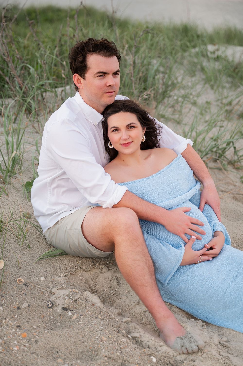 Intimate beach portrait on sandy dunes with coastal grass.