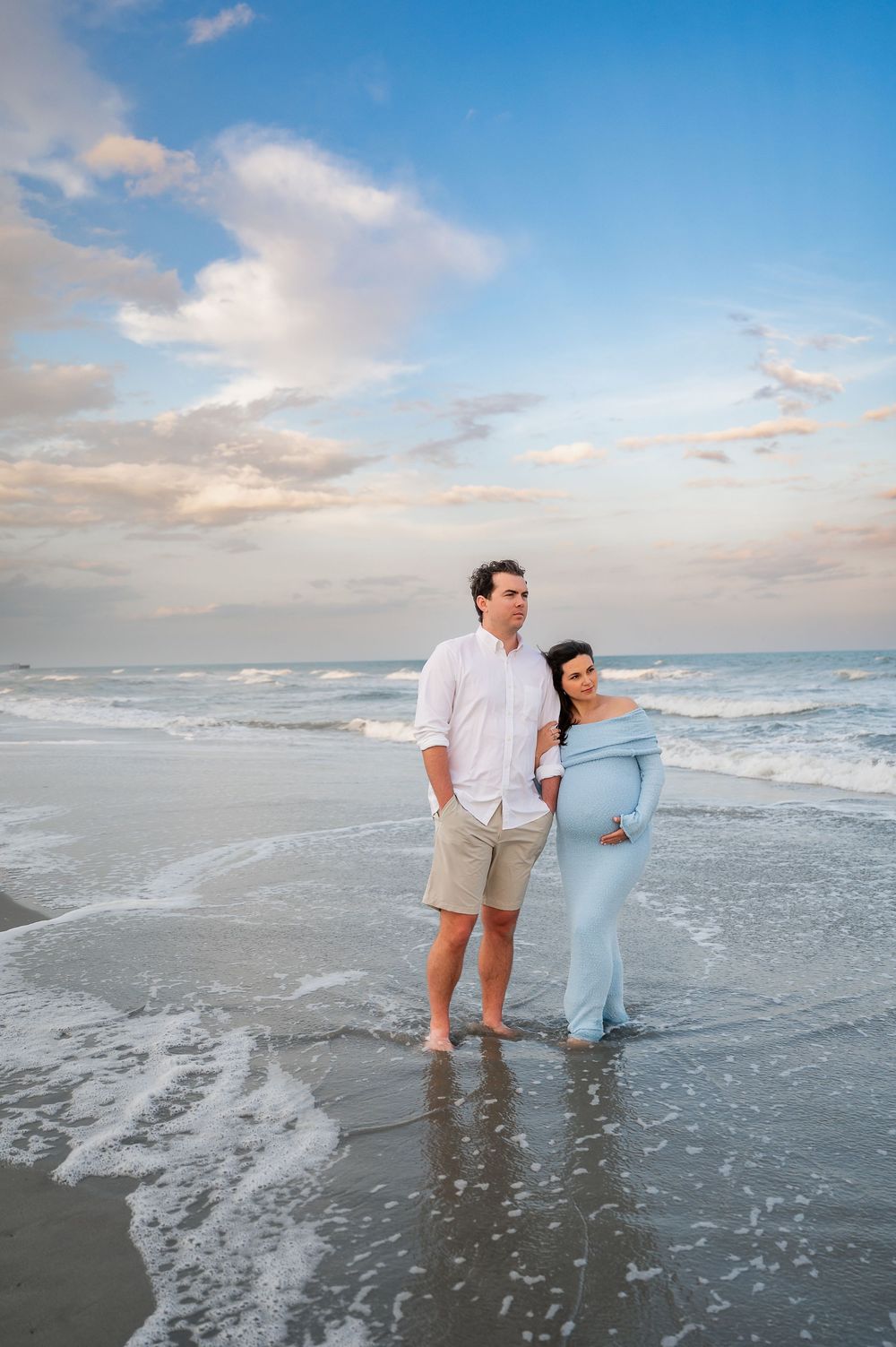 Couple enjoying sunset together while walking in the ocean waves.