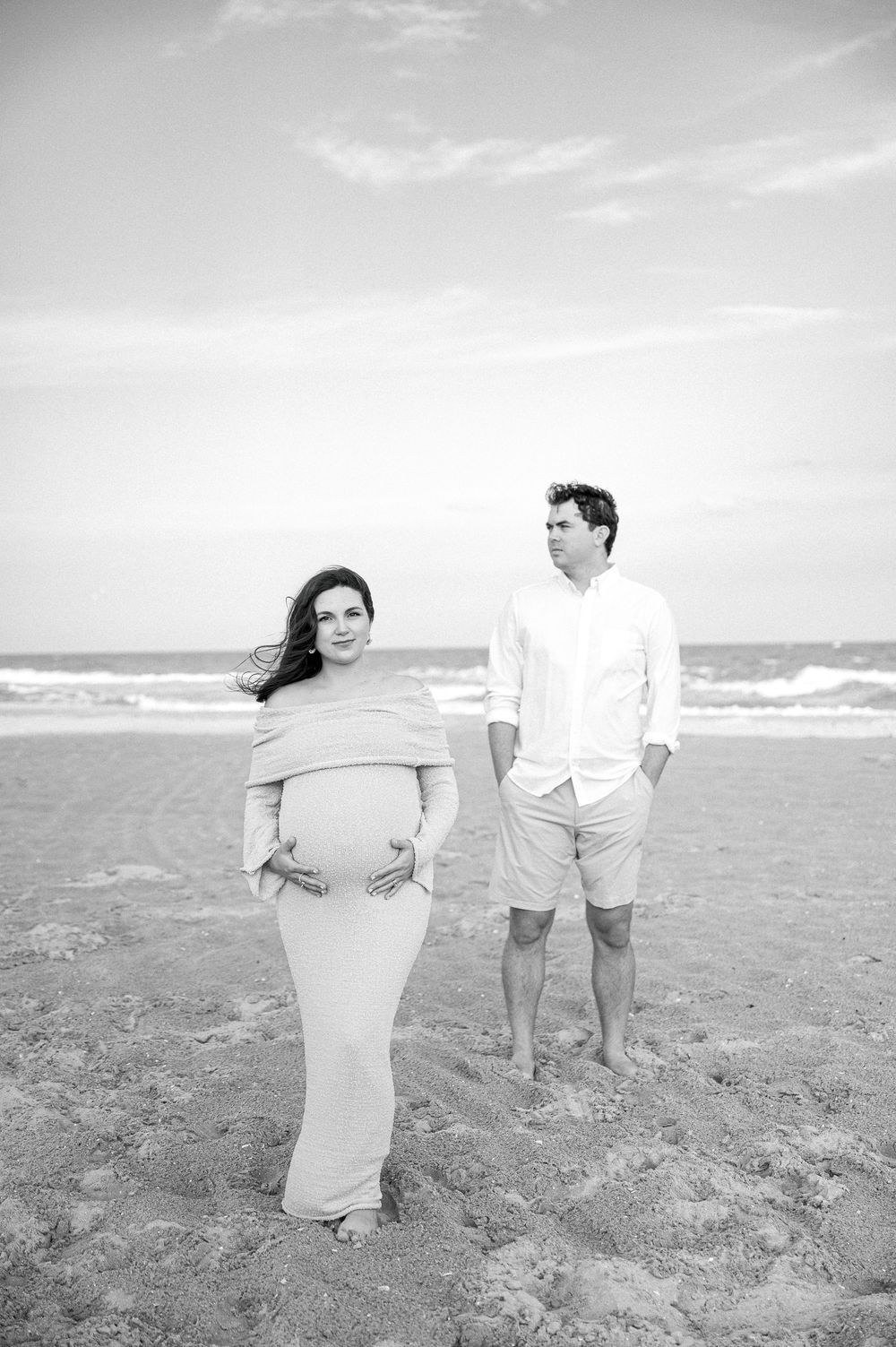 Black and white beach photos of couple interacting playfully on sandy shore.