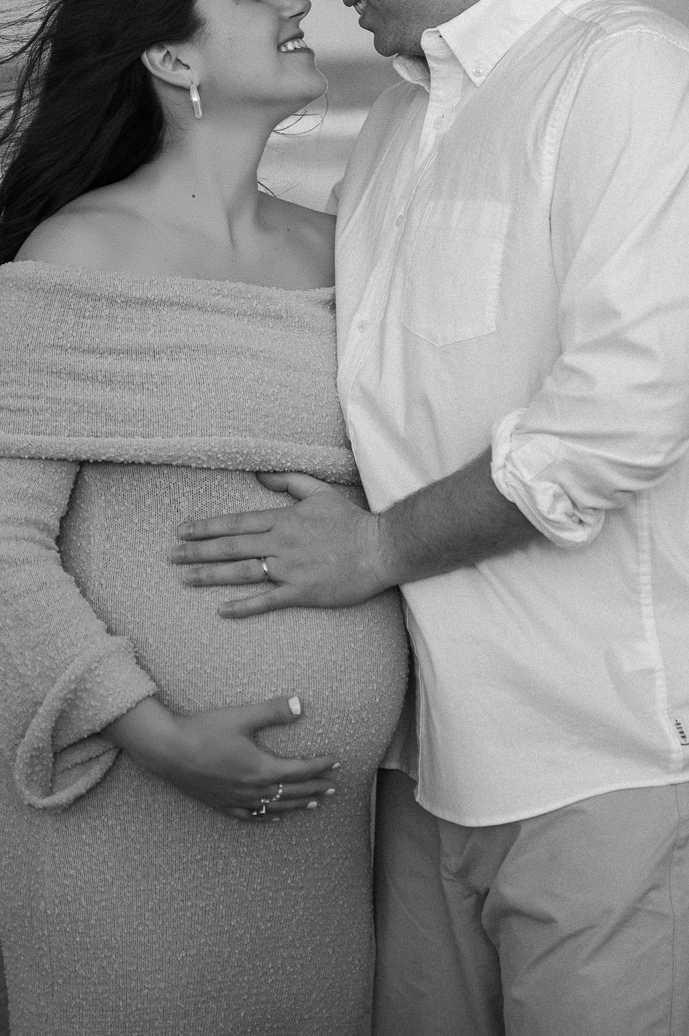 Black and white intimate maternity photos showing couple embracing.
