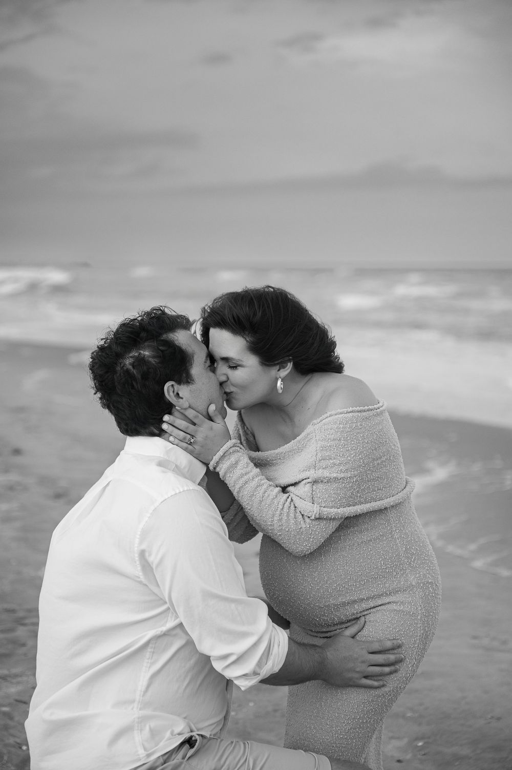 A romantic black and white beach photoshoot featuring an intimate moment between a couple.