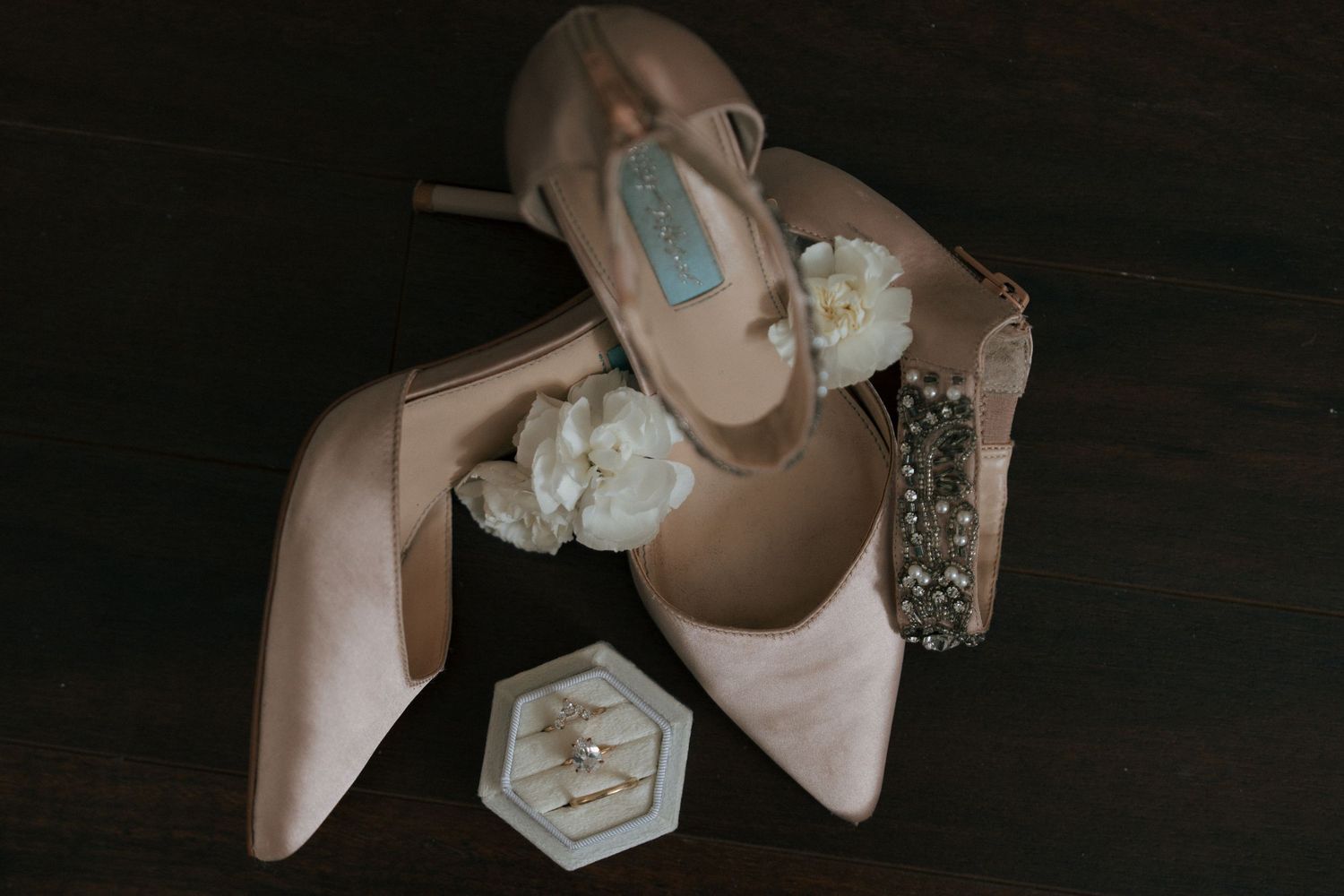 Close-up details of elegant bridal shoes and accessories including sparkly heels and delicate jewelry against dark background.