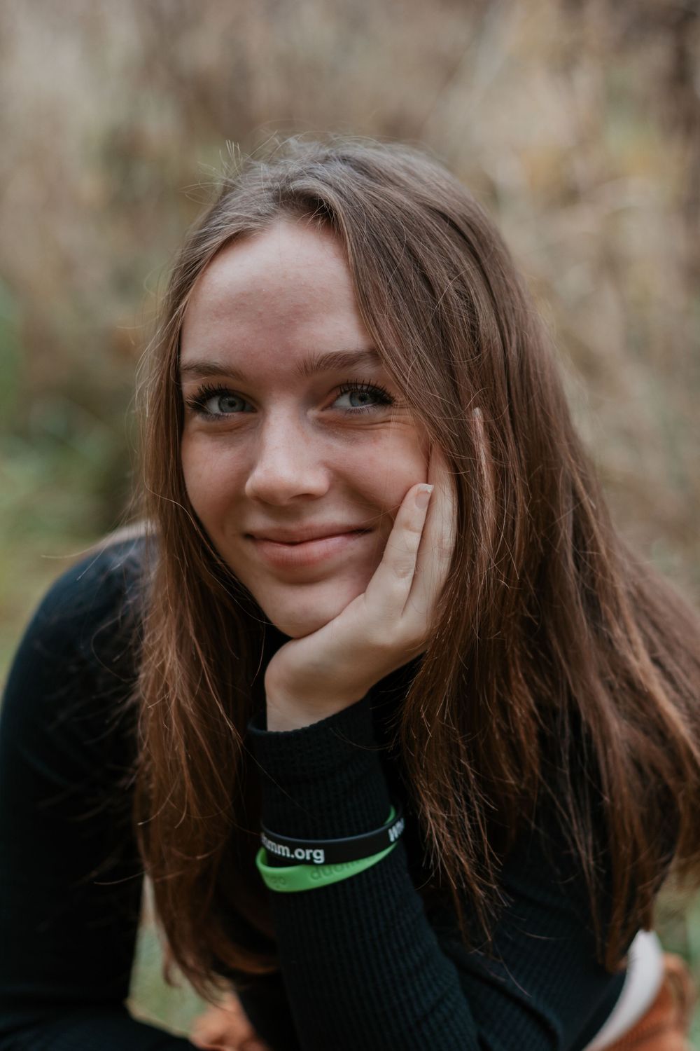 Person rests head on hand in close-up autumn portrait.