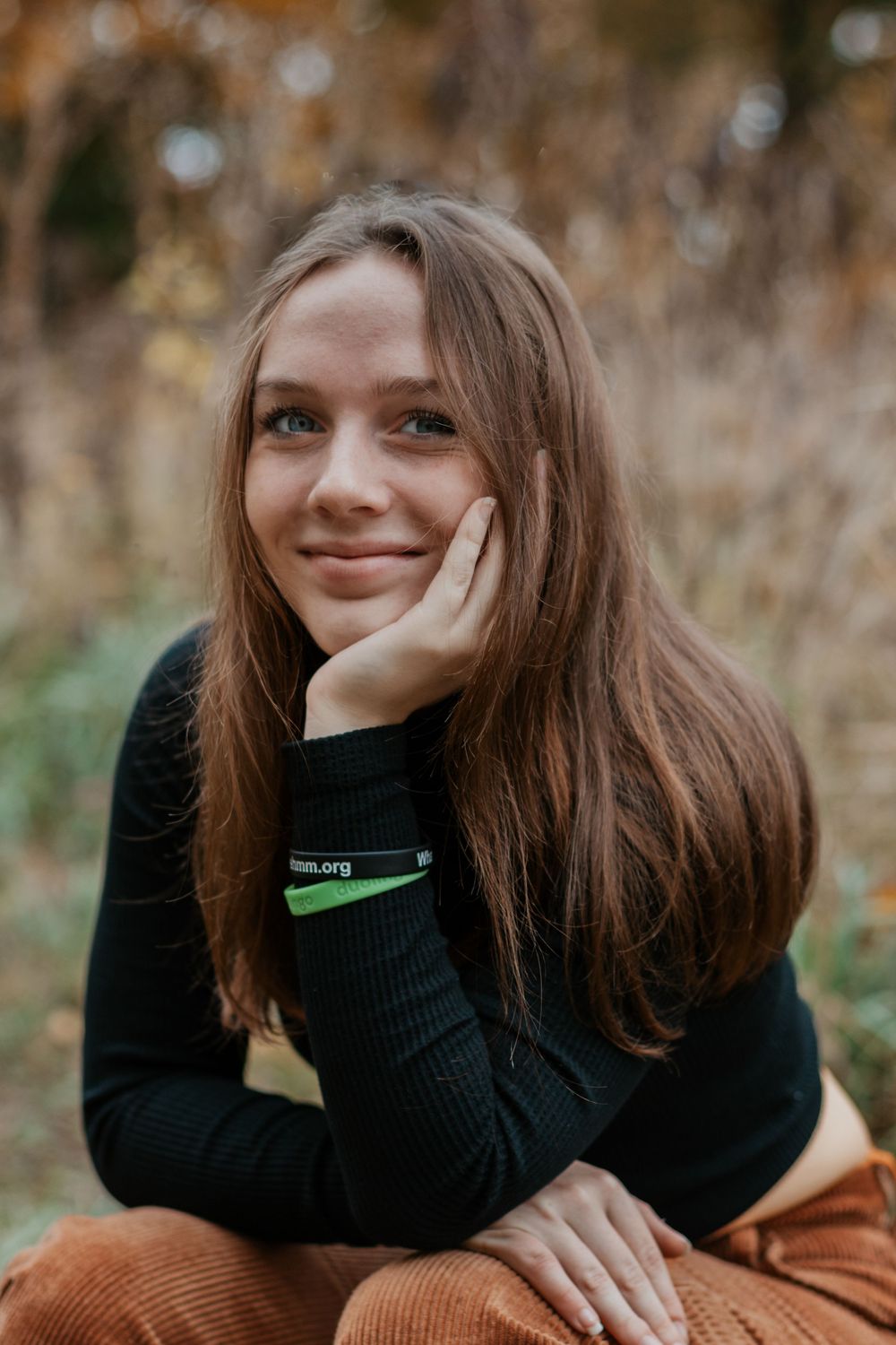 A series of autumn portraits showing someone in a black sweater and brown corduroy pants against fall foliage.