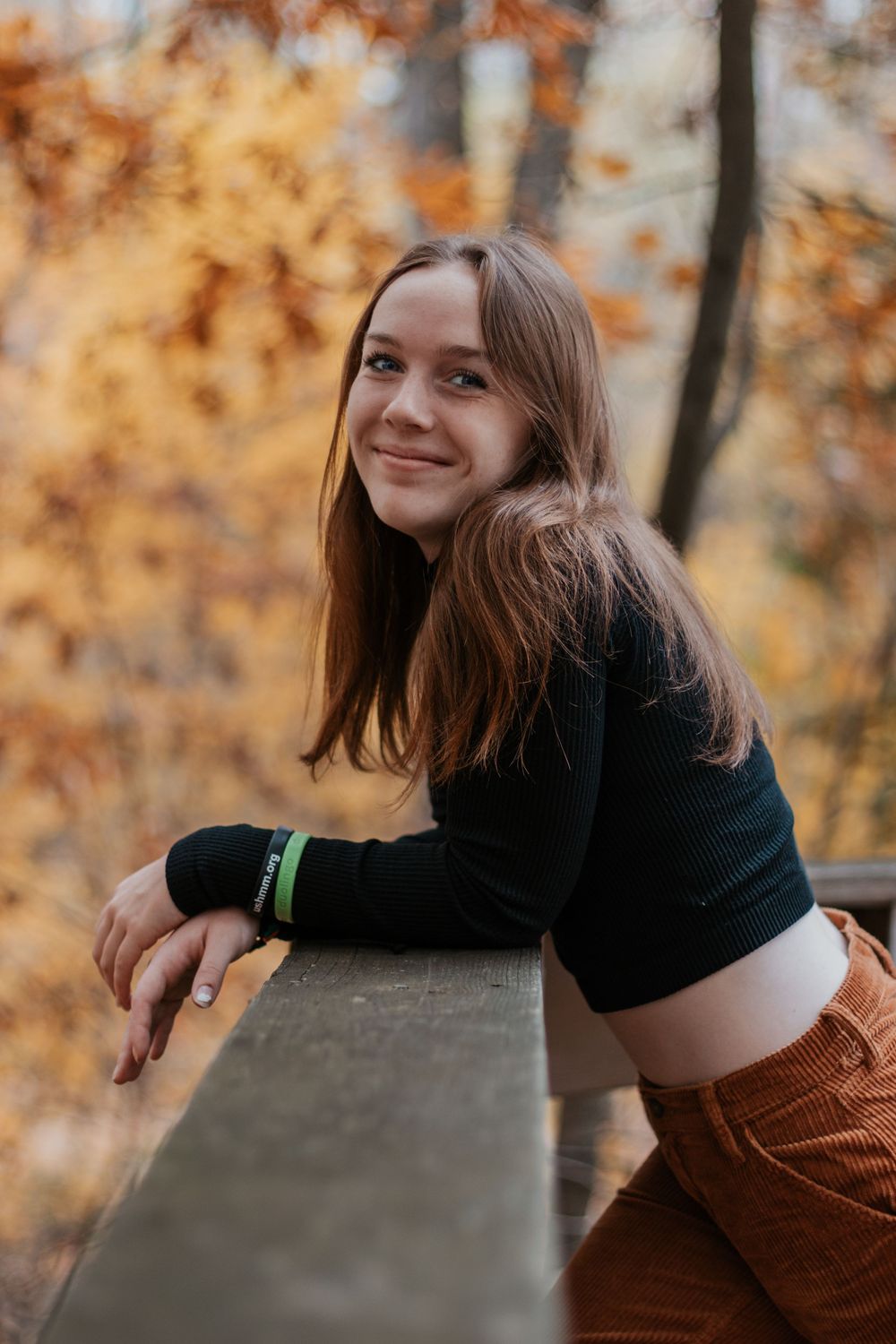 Casual autumn portraits taken on a wooden deck with fall foliage in the background.