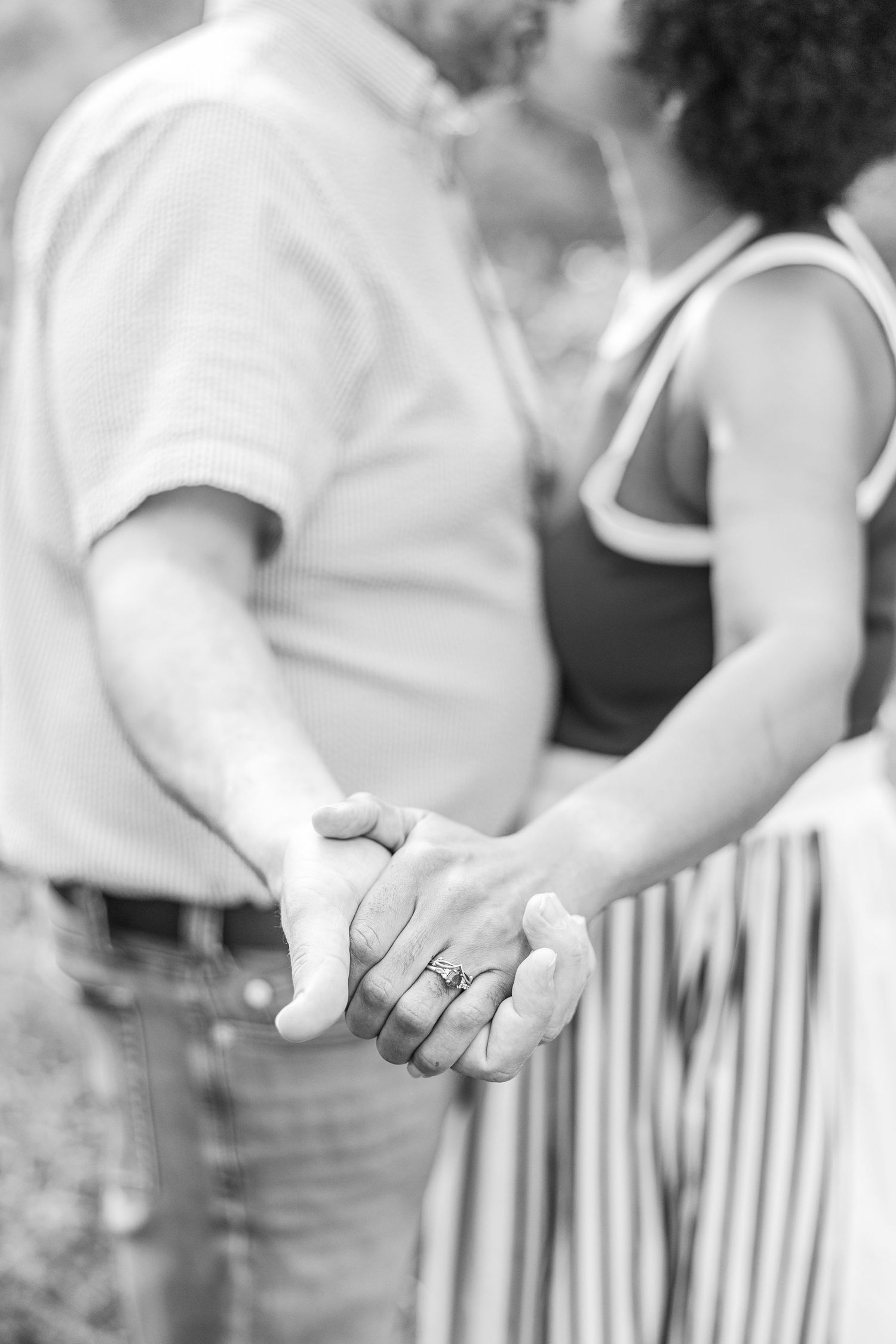 Close-up of hands showing engagement ring during outdoor photo session.