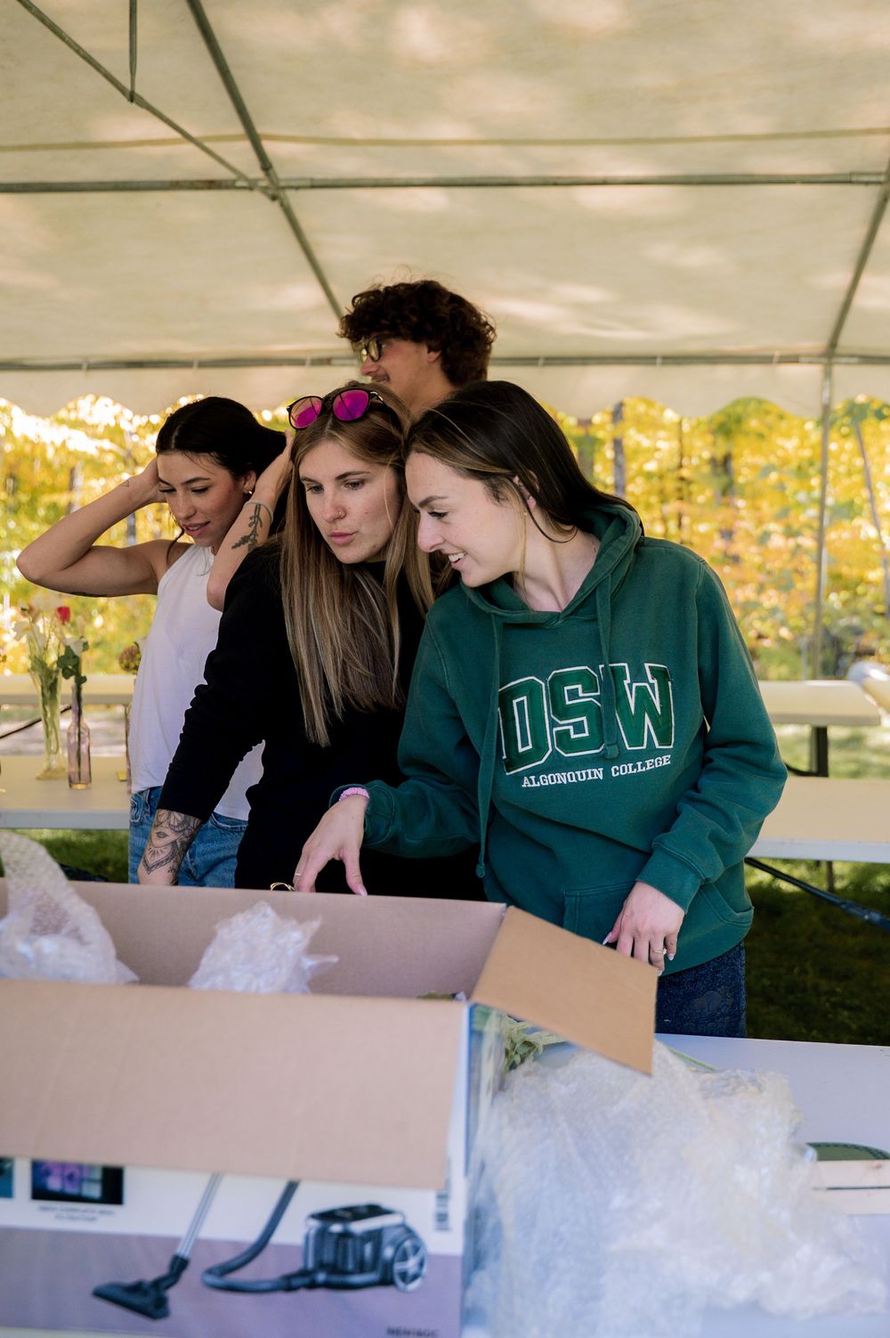 People looking through boxes filled with white packing material under a white tent.