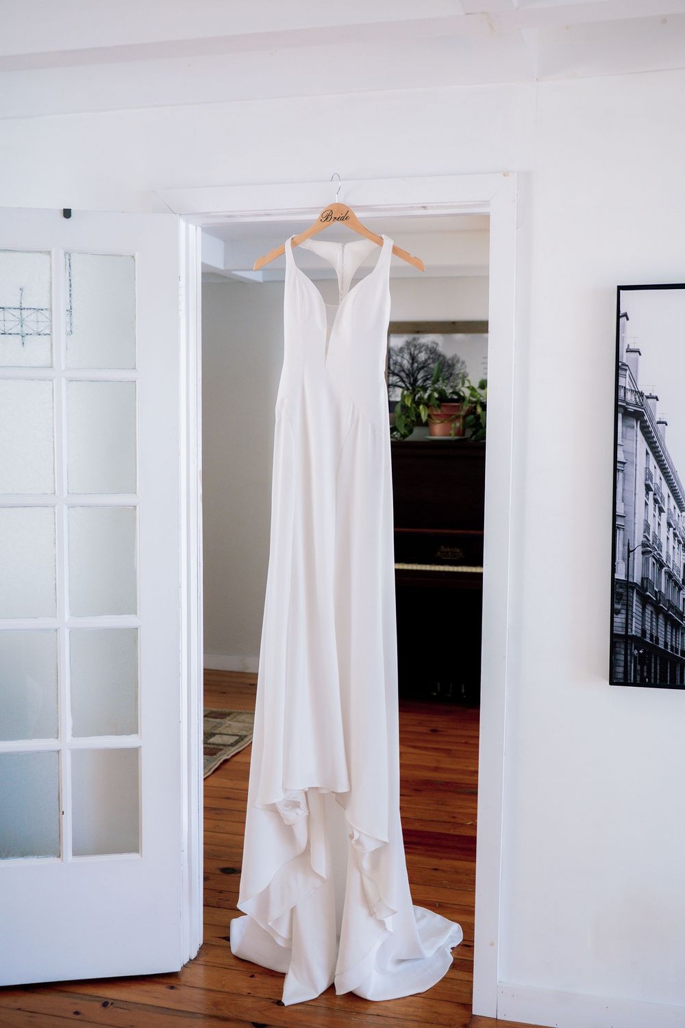 White wedding dress displayed in an elegant white room with french doors and hardwood floors.