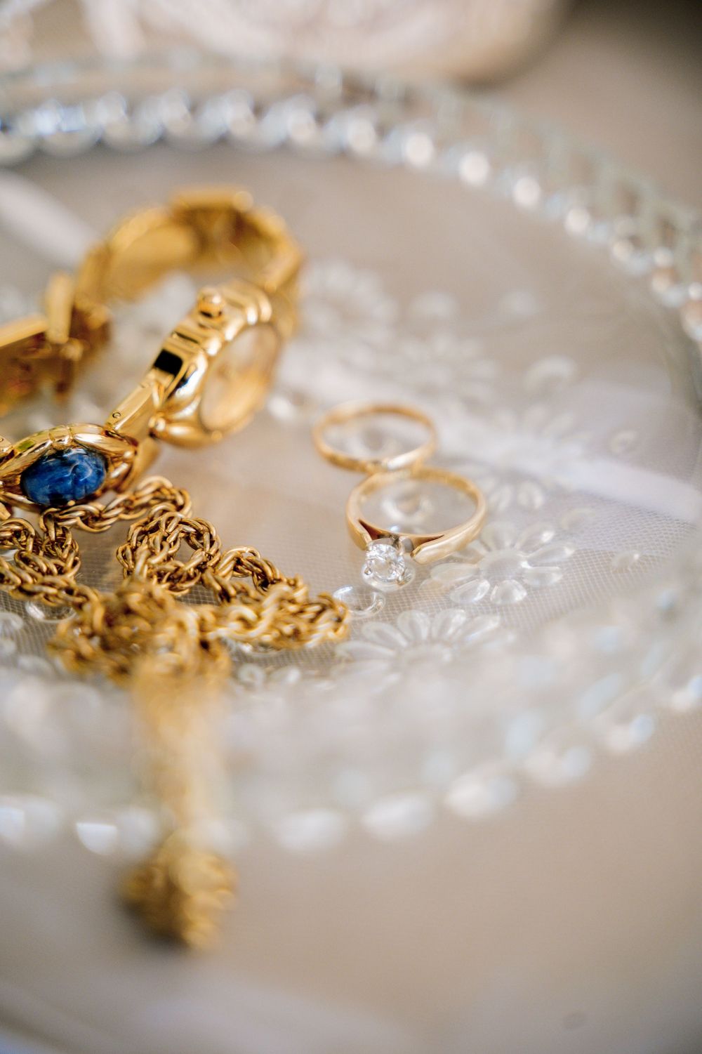 Gold jewelry and rings arranged on delicate lace fabric.