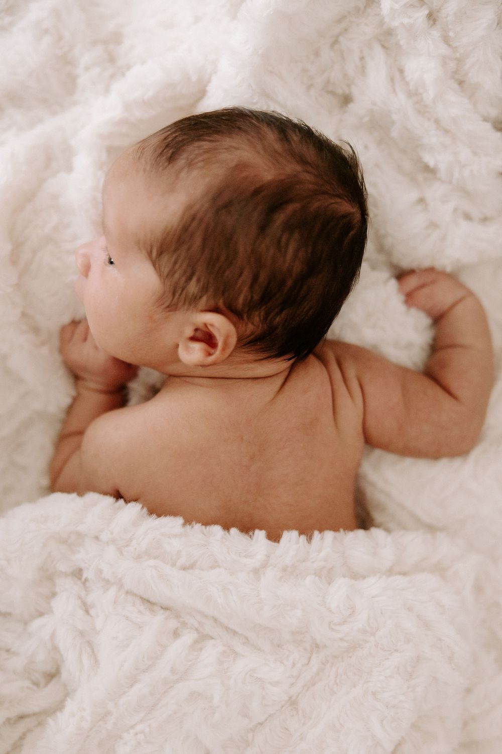 A sleeping baby rests peacefully on soft white lace bedding.