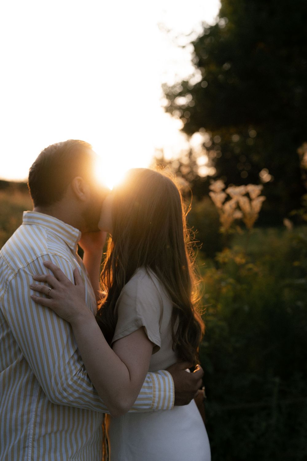 Romantic sunset silhouette of couple embracing in golden light.