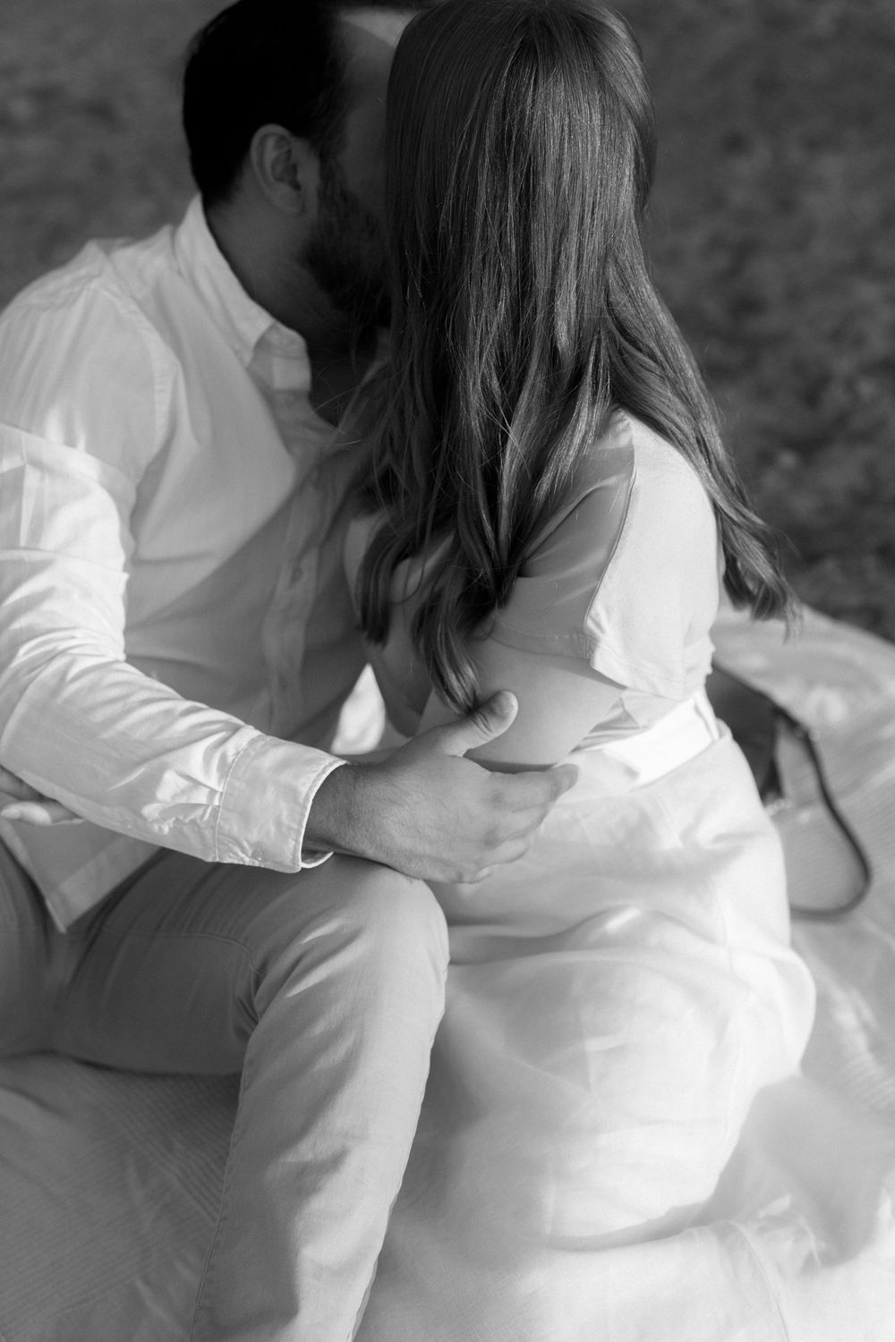 Intimate black and white portrait of a couple in white clothing sharing a tender moment.