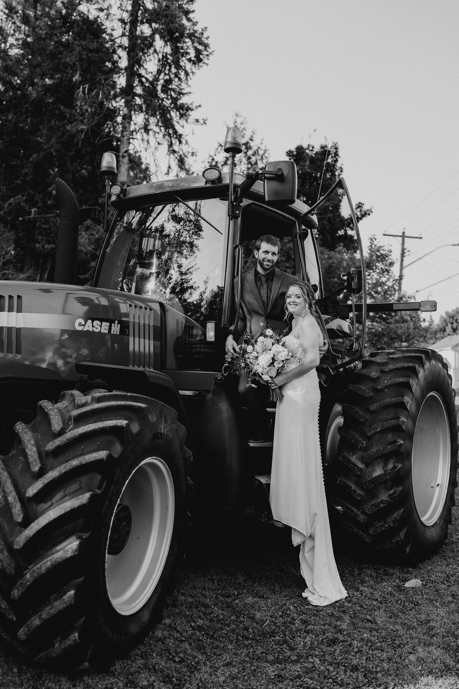 black and white of bride and groom with their tractor