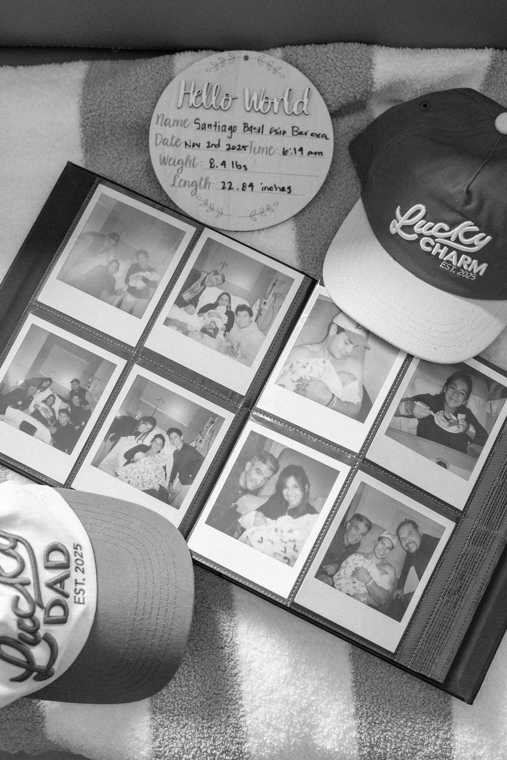 Black and white photo showing a photo album with polaroid pictures and two baseball caps with "Lucky" branding visible.