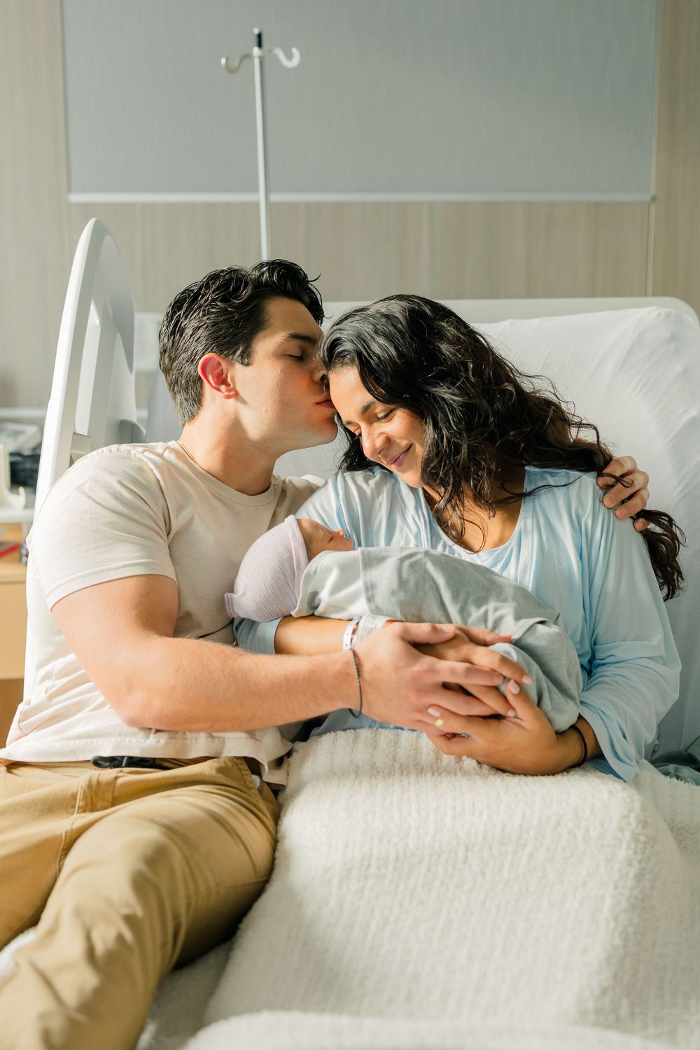 Couple relaxing together on white couch while looking at smartphone screen in sunlit room.