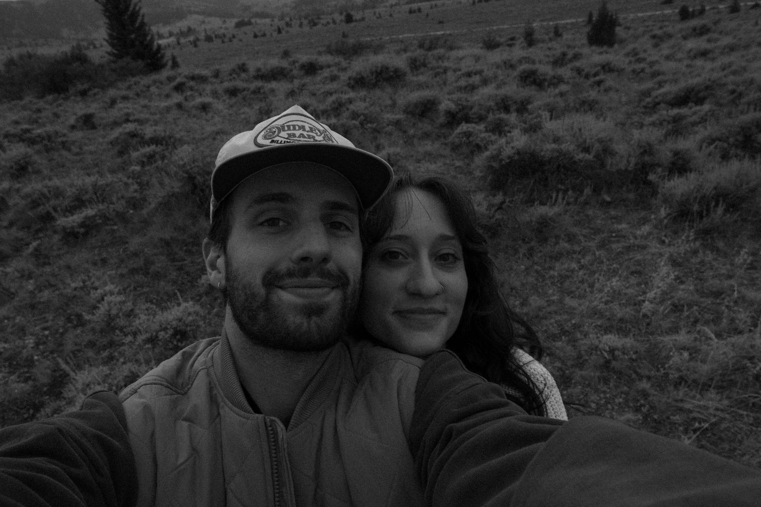 Close-up selfie portrait with mountain landscape backdrop.